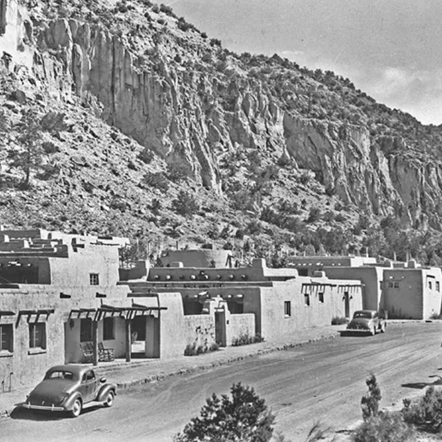 black and white photo of low adobe building along dirt street
